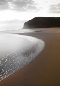 Dark brown sand and cliffs at the beach